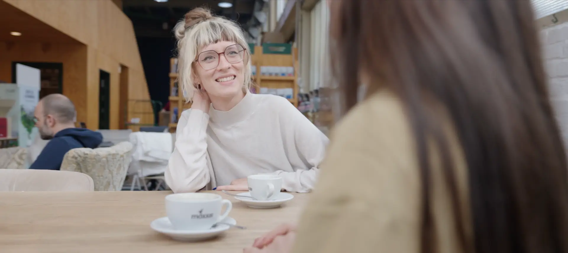 Zwei Kolleginnen unterhalten sich bei einer Tasse Kaffee an einem Tisch