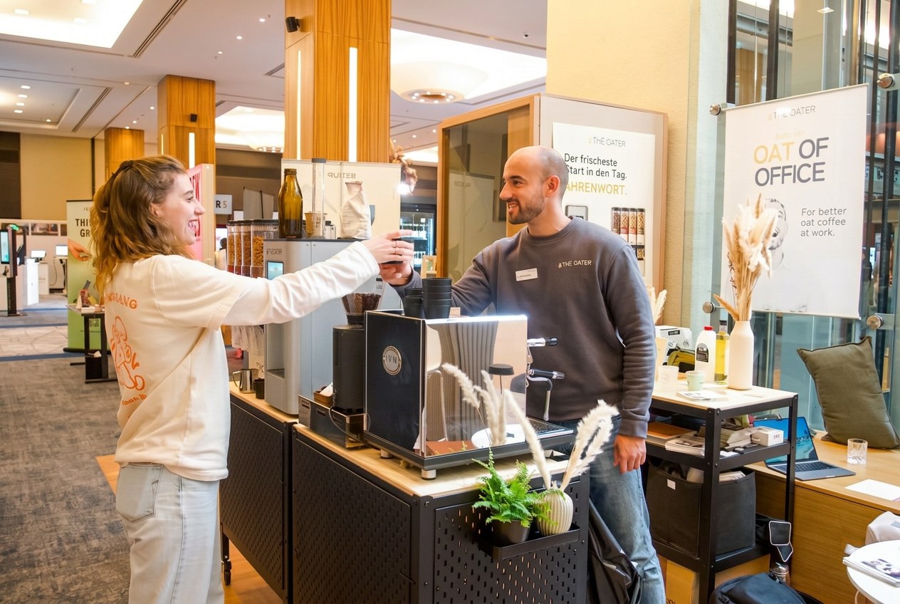 Henrik und eine Besucherin stoßen an der The Oater Kaffeebar mit ihren Drinks an