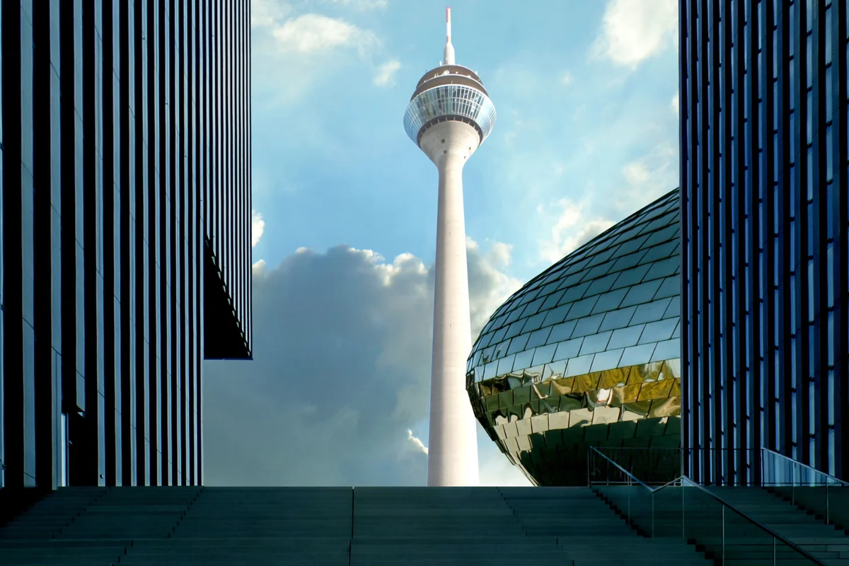 Düsseldorfer Medienhafen mit Rheinturm und metallischer Kuppel hinter einer breiten Freitreppe