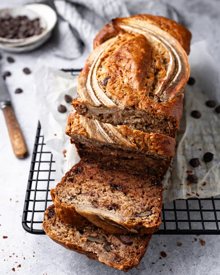 Angeschnittenes Banana Bread mit Bananenhälften auf einem Kuchengitter